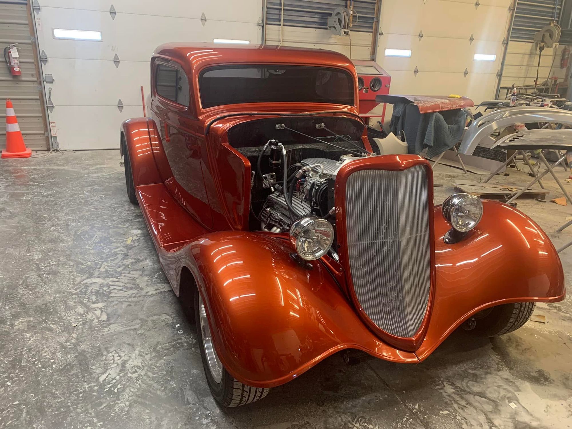 Candy orange classic coupe with its engine on show in the workshop